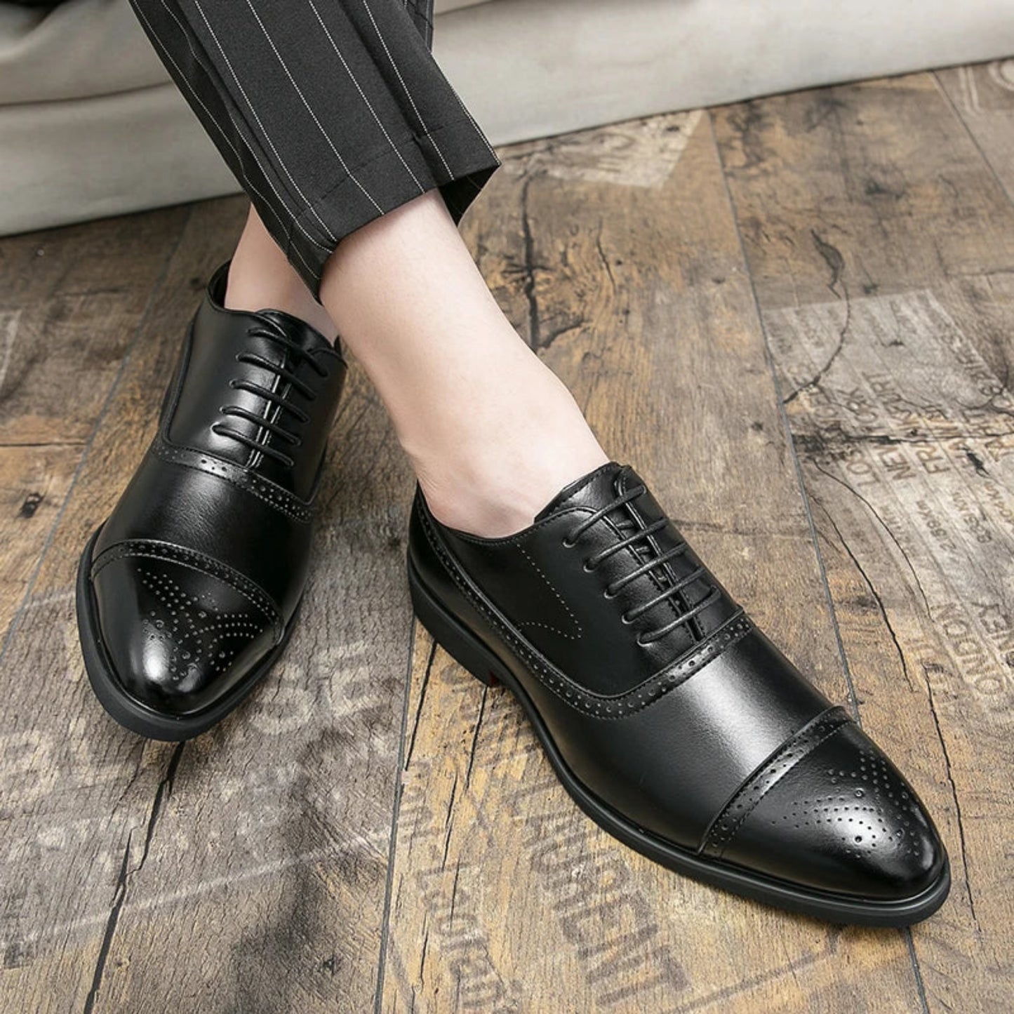 Black dress shoes worn on a wooden floor