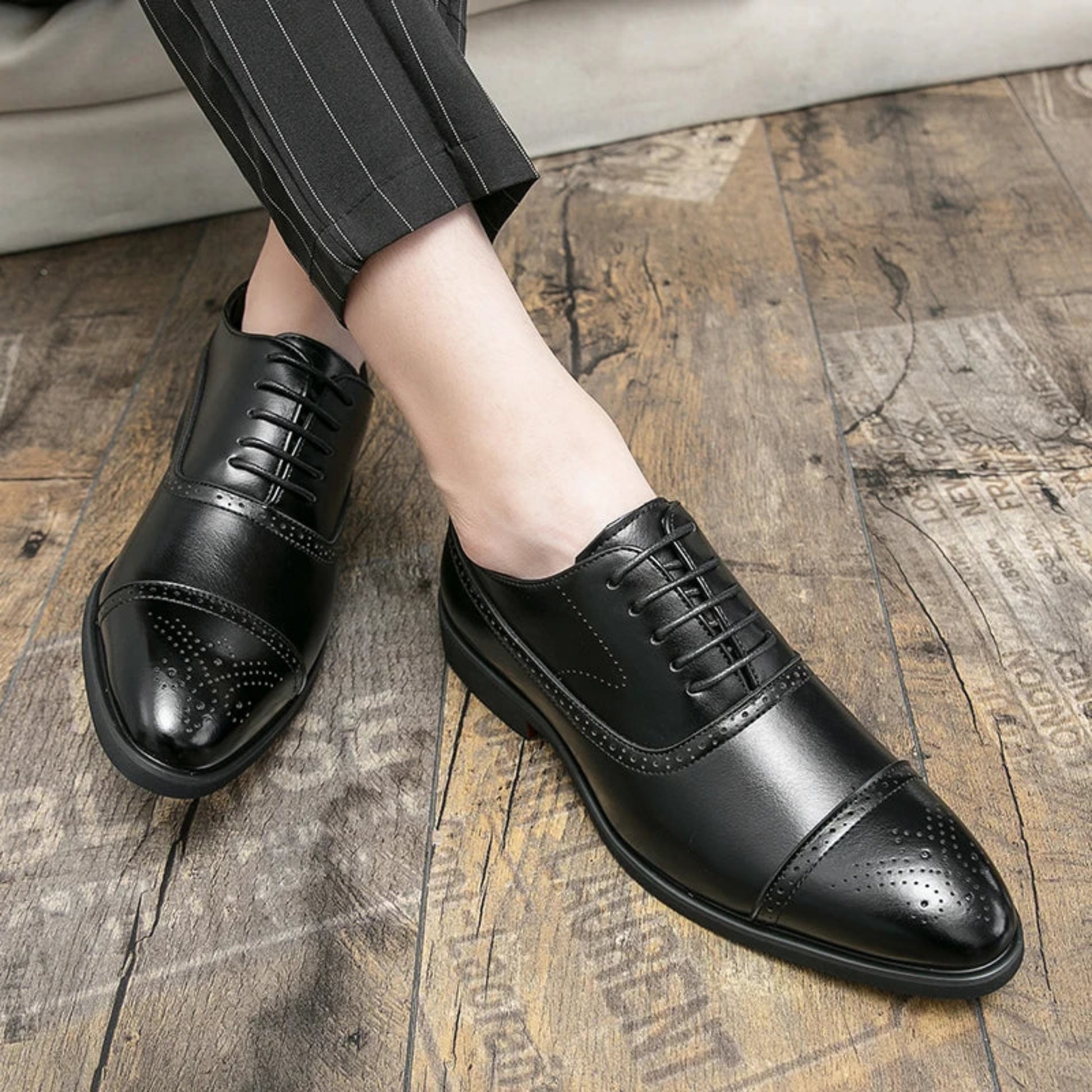 Black dress shoes worn on a wooden floor
