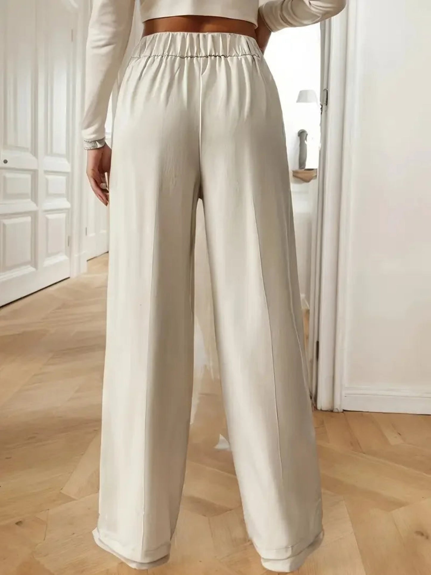 Person wearing white wide-leg pants in a minimal indoor setting