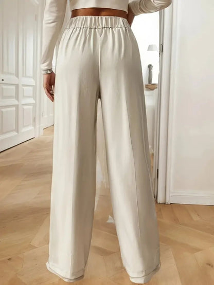 Person wearing white wide-leg pants in a minimal indoor setting