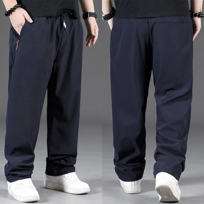 Two pairs of dark blue pants worn by models on a gray background
