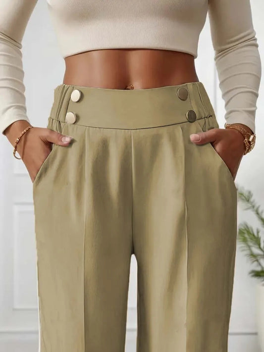 Beige high-waisted pants with button details worn by a person, against a neutral background.