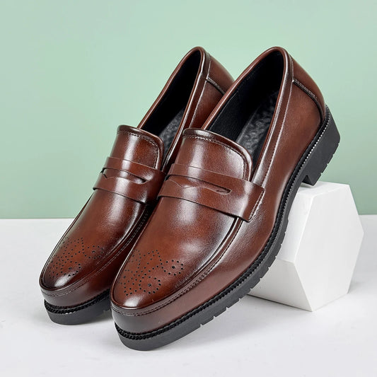 Brown leather loafers on a white platform with a light green background
