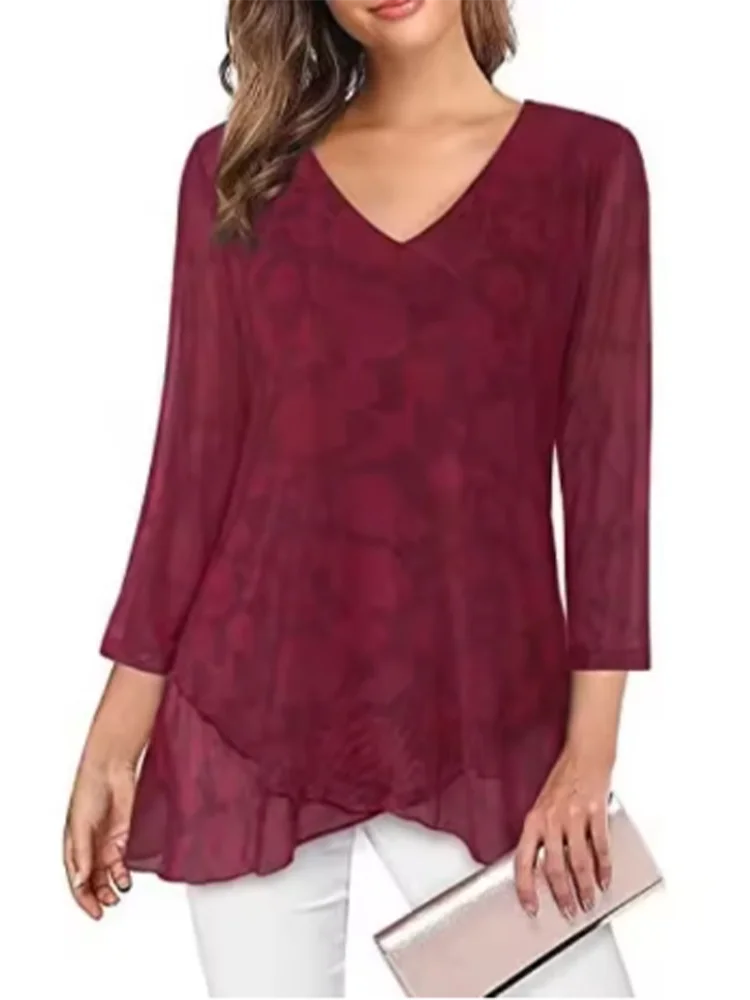 Woman wearing a burgundy floral blouse with white pants on a white background