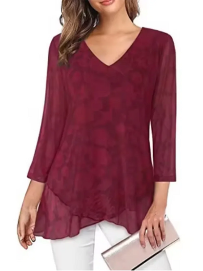 Woman wearing a burgundy floral blouse with white pants on a white background