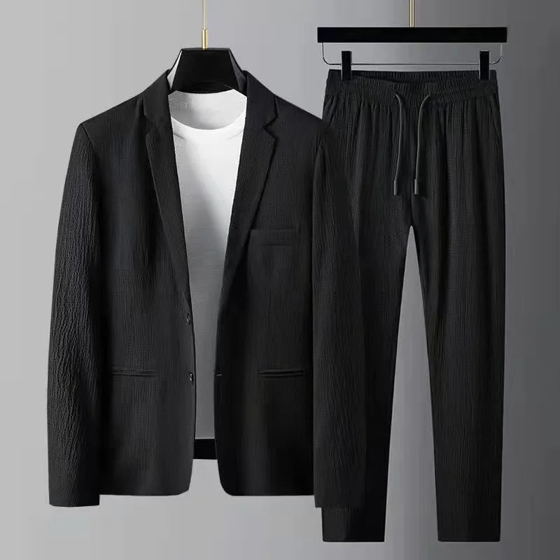 Black blazer and pants set on hangers against a gray background