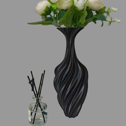 Black textured vase with white flowers on a surface with decorative items.