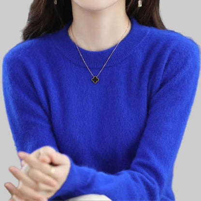 Person wearing a blue sweater with a necklace featuring a clover pendant.