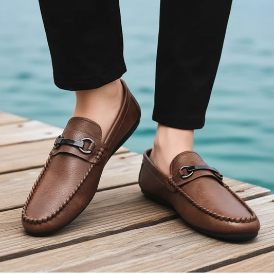 Brown loafers worn with black pants on a neutral background