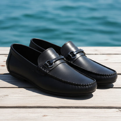 Black leather loafers with a silver buckle on a textured surface