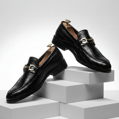 Black leather loafers with gold buckles on a white background