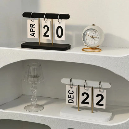 Two calendar sets on a shelf with a clock and decorative items.