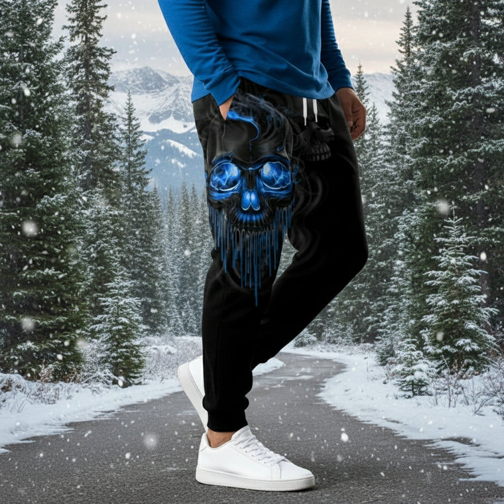 Black jogger pants with blue skull design worn by a person on a gray background