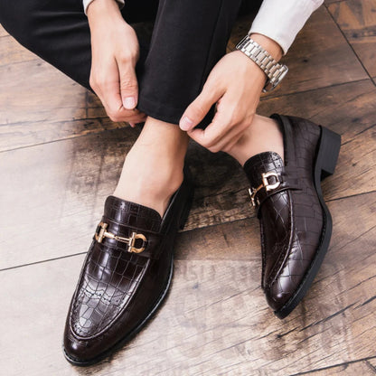 Person wearing brown crocodile-patterned loafers on a wooden floor