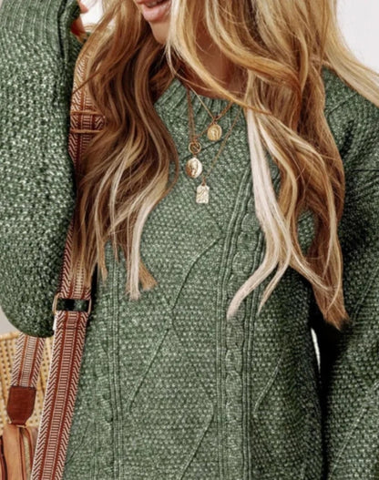 Person wearing a green textured coat with long blonde hair and a strap over shoulder.