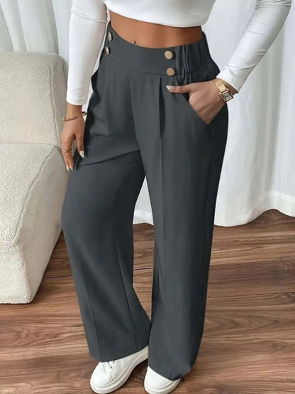 Person wearing gray wide-leg pants with a white top and white sneakers indoors.