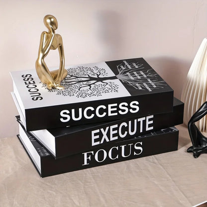Stack of books with motivational phrases on a surface, accompanied by decorative statues.