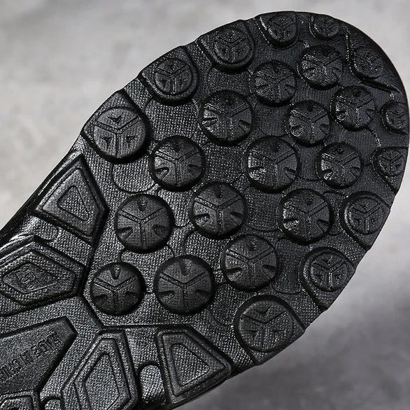 Close-up of a black shoe sole with tread pattern on a gray background