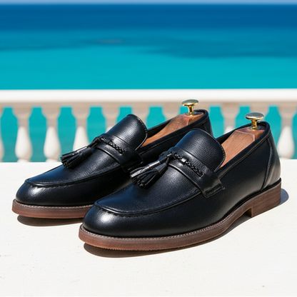 Pair of black loafers with tassels on a grid surface