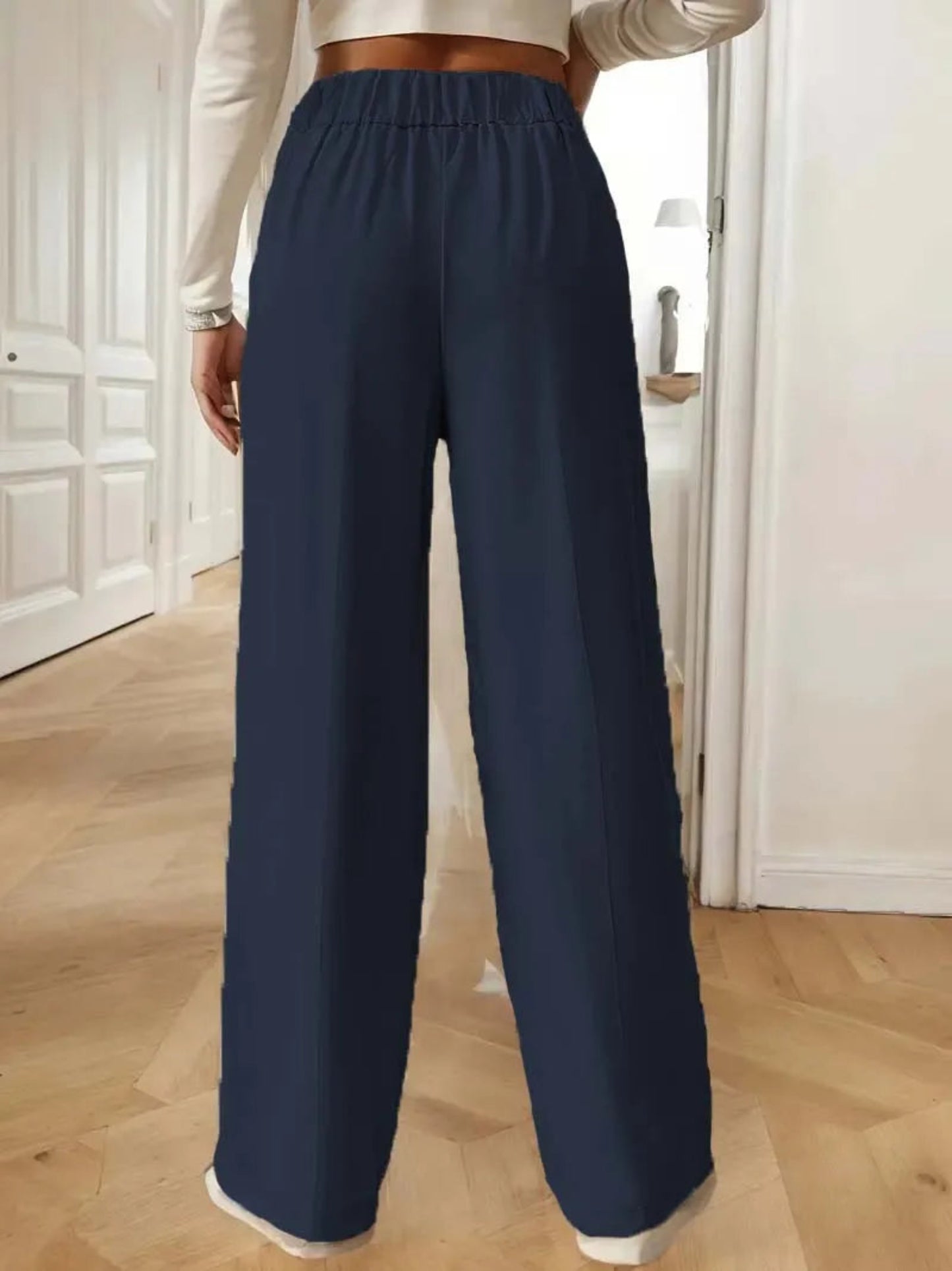 Navy blue wide-leg pants worn by a person indoors on a wooden floor.