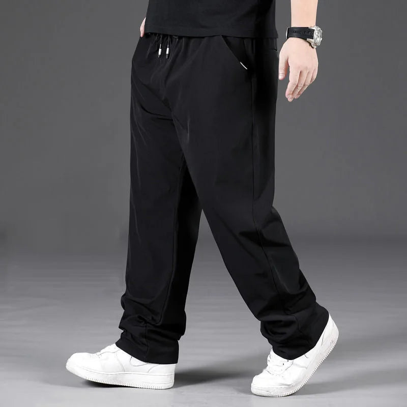 Person wearing black pants and white sneakers on a gray background