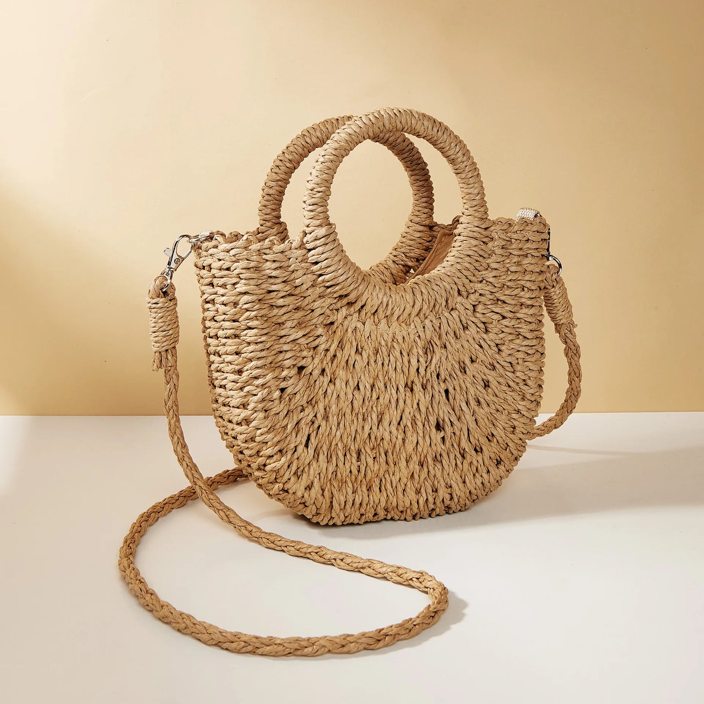 Woven straw handbag with a strap on a beige background