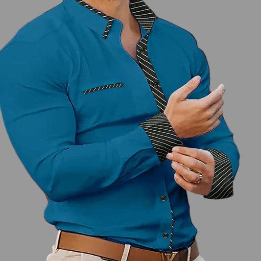 Man wearing a blue shirt with black striped collar and cuffs in an indoor setting.