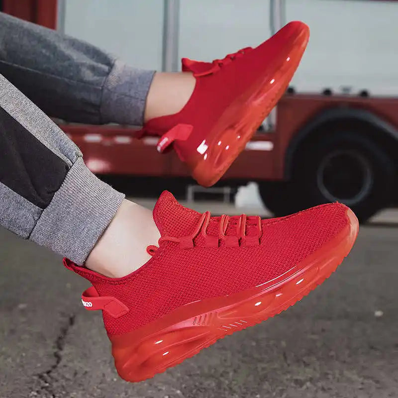 Red sneakers worn with gray pants, with a blurred background of a red vehicle.