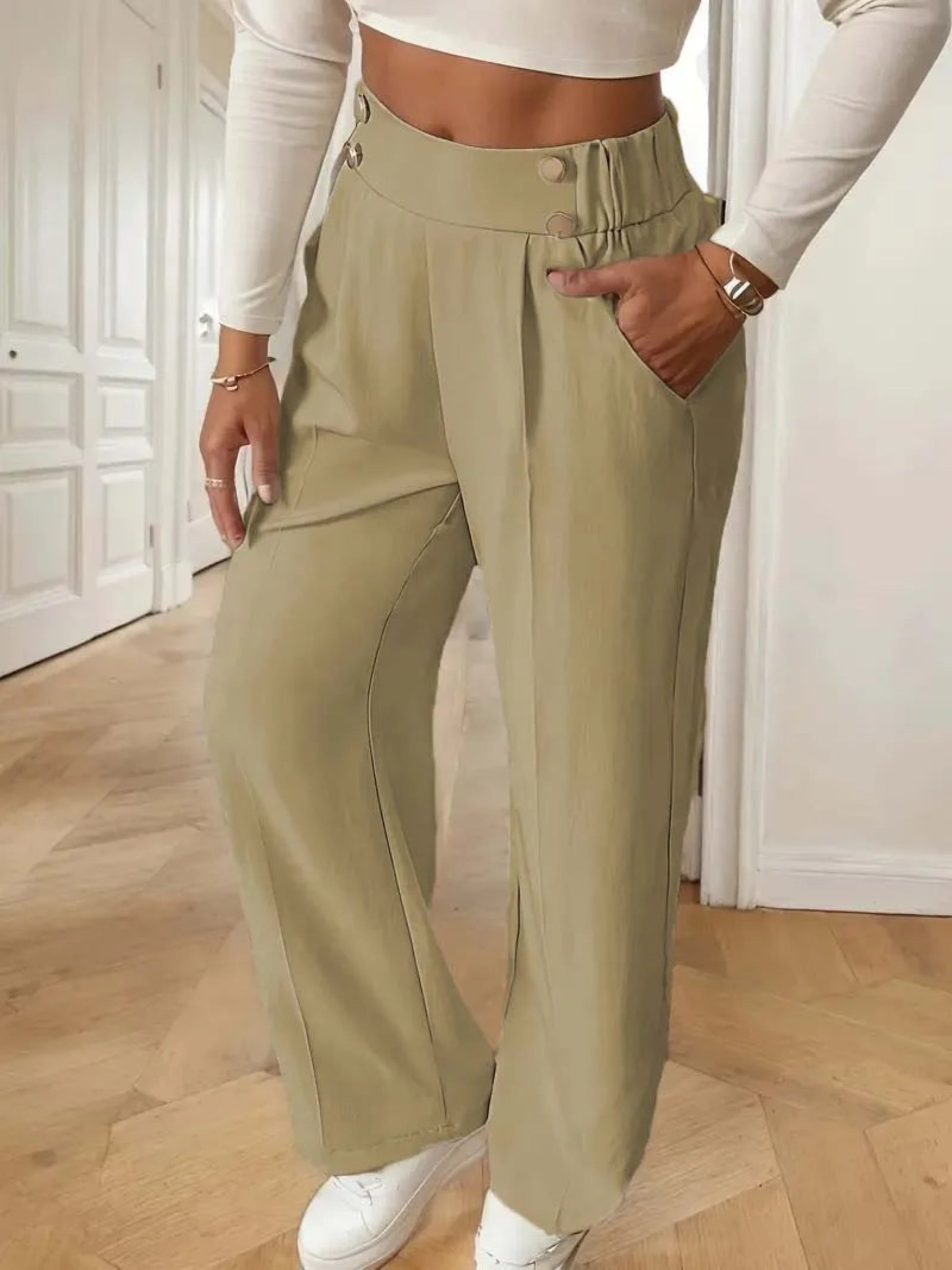 Person wearing olive green pants and white sneakers indoors.