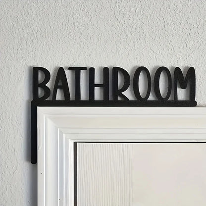 Black 'Bathroom' sign on a white door frame against a light gray wall.