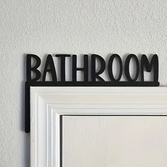 Black 'Bathroom' sign on a white door frame against a light gray wall.