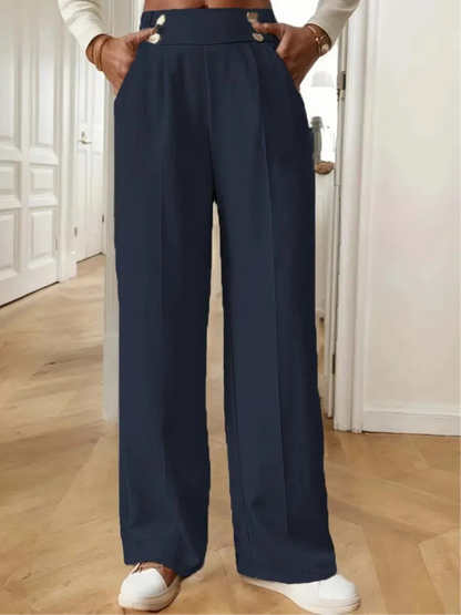 Person wearing navy wide-leg pants with a white top and white shoes indoors.