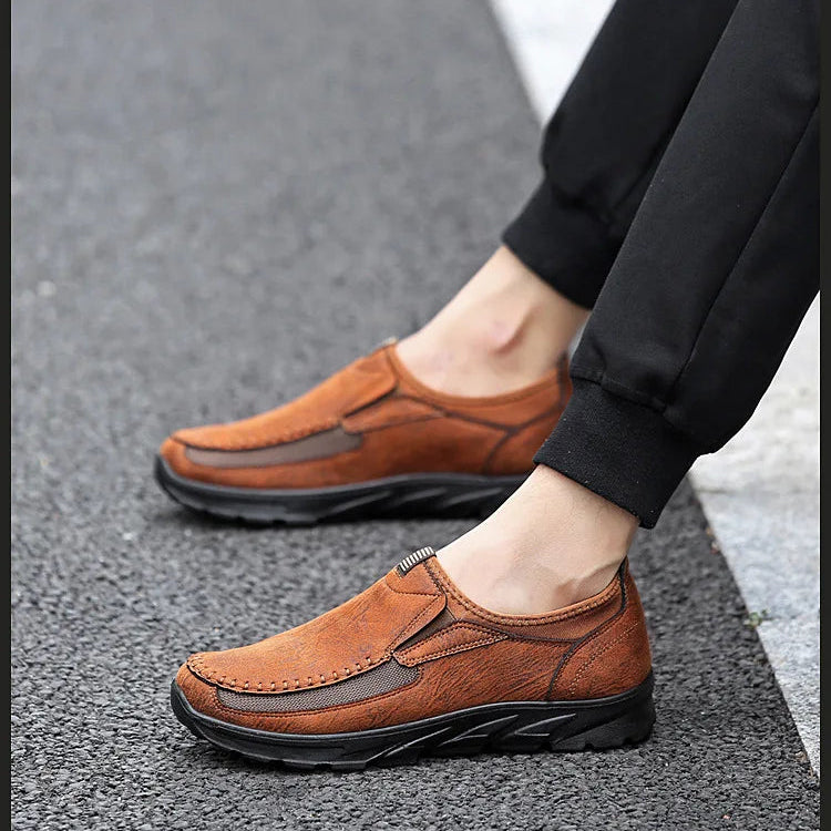 Brown leather shoes worn on a gray pavement