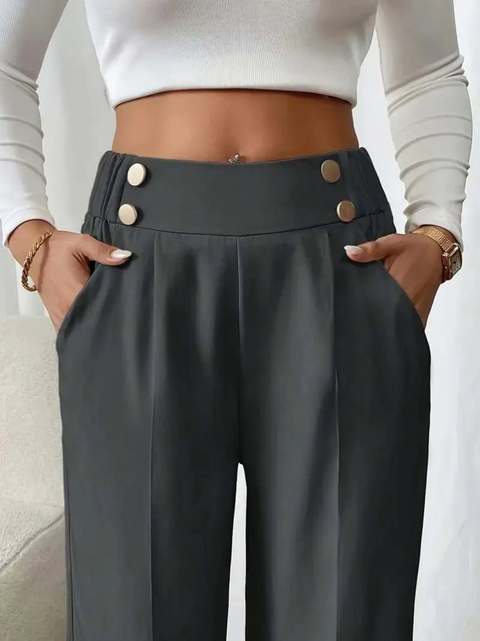 Person wearing dark gray pants with button details and a white top.