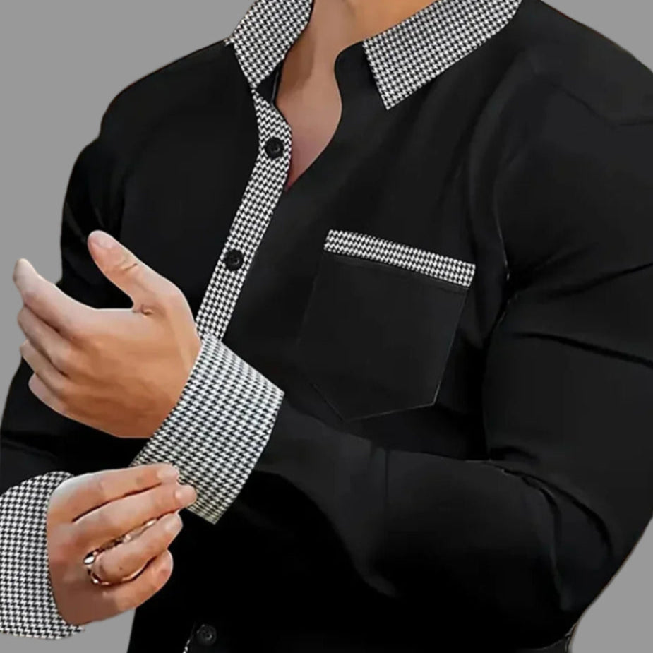 Man wearing a black shirt with checkered collar and cuffs in an indoor setting