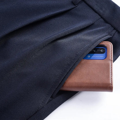 Smartphone in a brown leather case peeking out from a black fabric pocket.