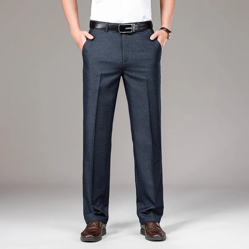 Person wearing dark gray pants with a white shirt and brown shoes on a gray background