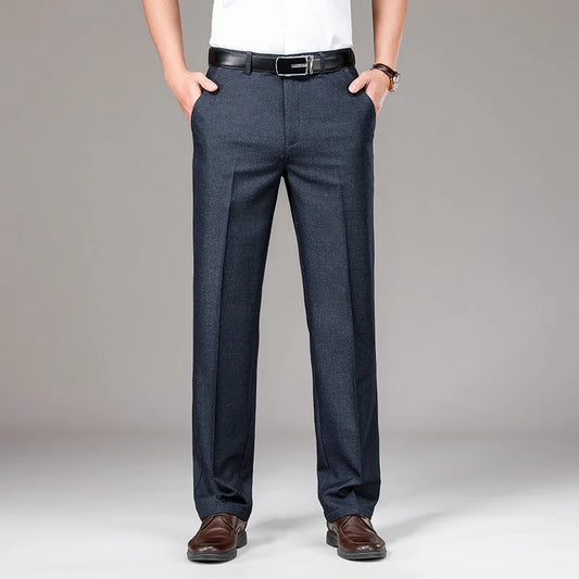 Person wearing dark gray pants with a white shirt and brown shoes on a gray background
