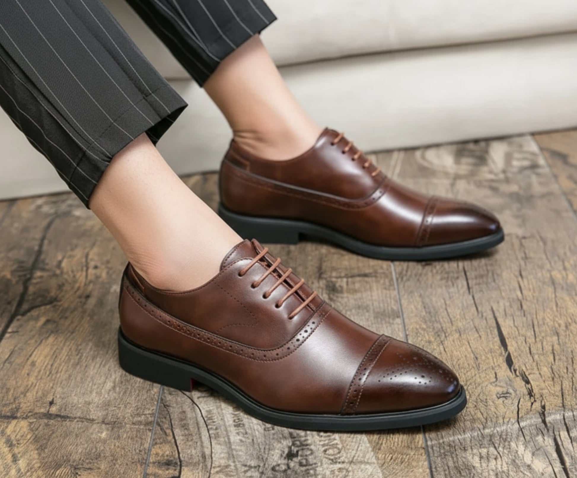 Brown leather dress shoes worn indoors on a wooden floor.